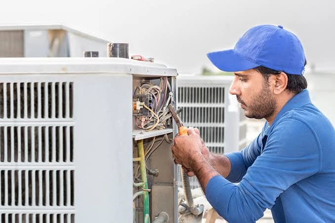 Technician repairing wiring in an outdoor air conditioning unit