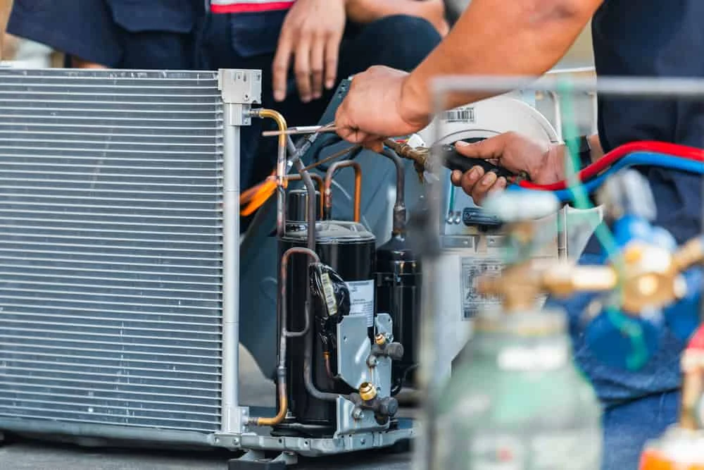 Close-up of technicians repairing refrigerant tubing in an air conditioning system